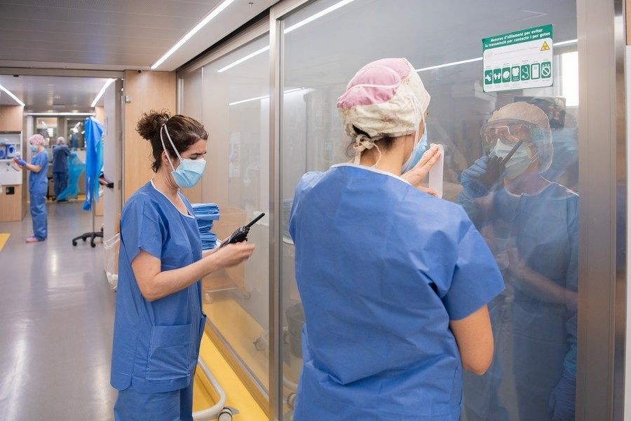 Medical workers communicate with colleagues inside a ward at a hospital in Barcelona, Spain, April 8, 2021. (Photo by Francisco Avia/Xinhua/IANS)